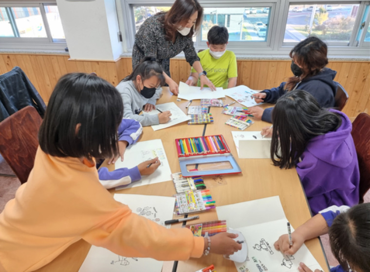 책상에 앉아 그림 그리는 아이들 사진